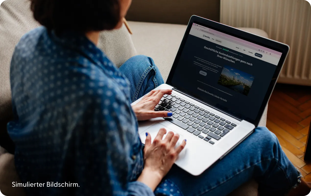 Person mit einem Laptop, auf dem eine simulierte Remitly Business-Landingpage abgebildet ist.