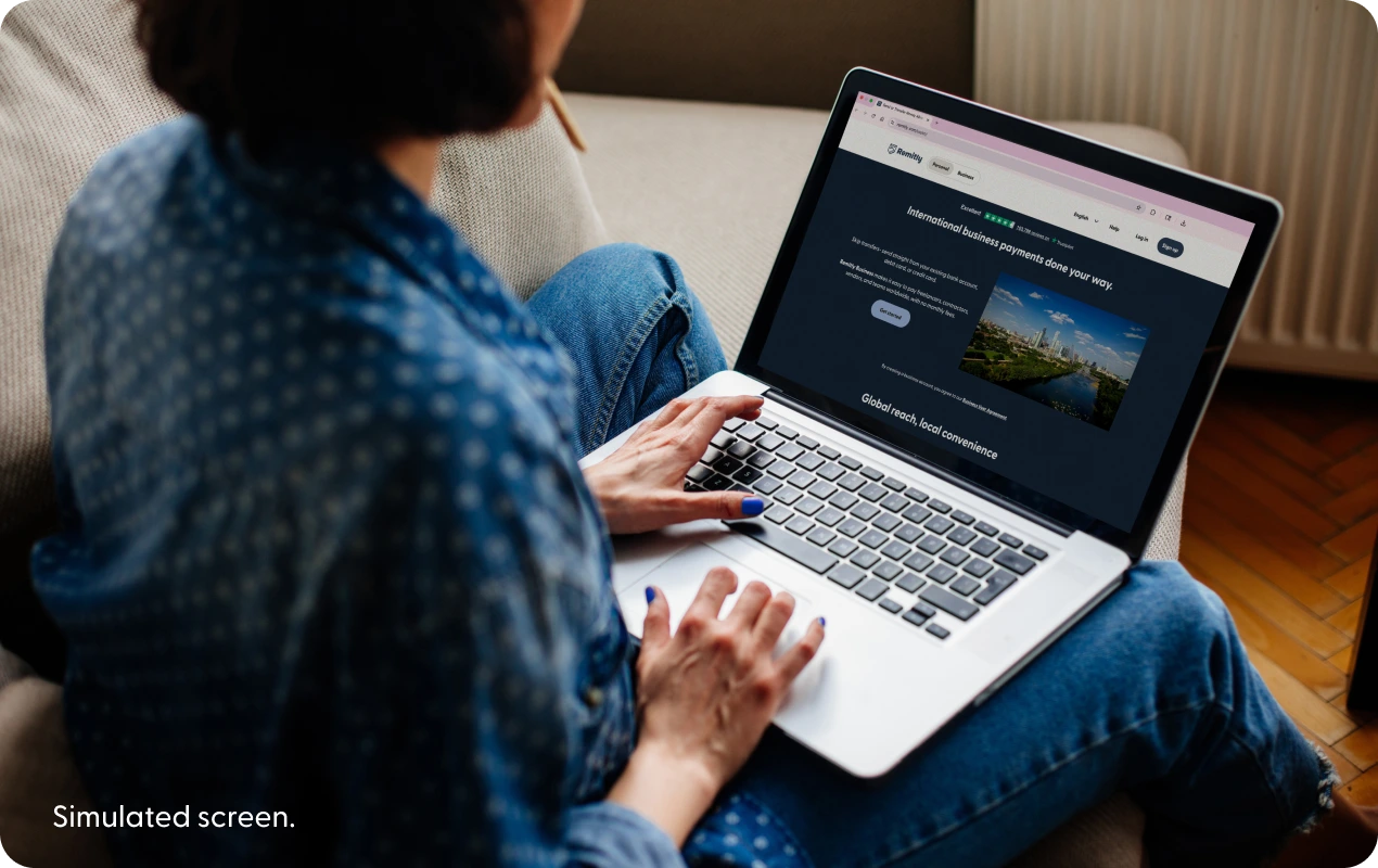Remitly Business 랜딩 페이지(시뮬레이션)를 노트북 화면에 띄워 놓은 사람.