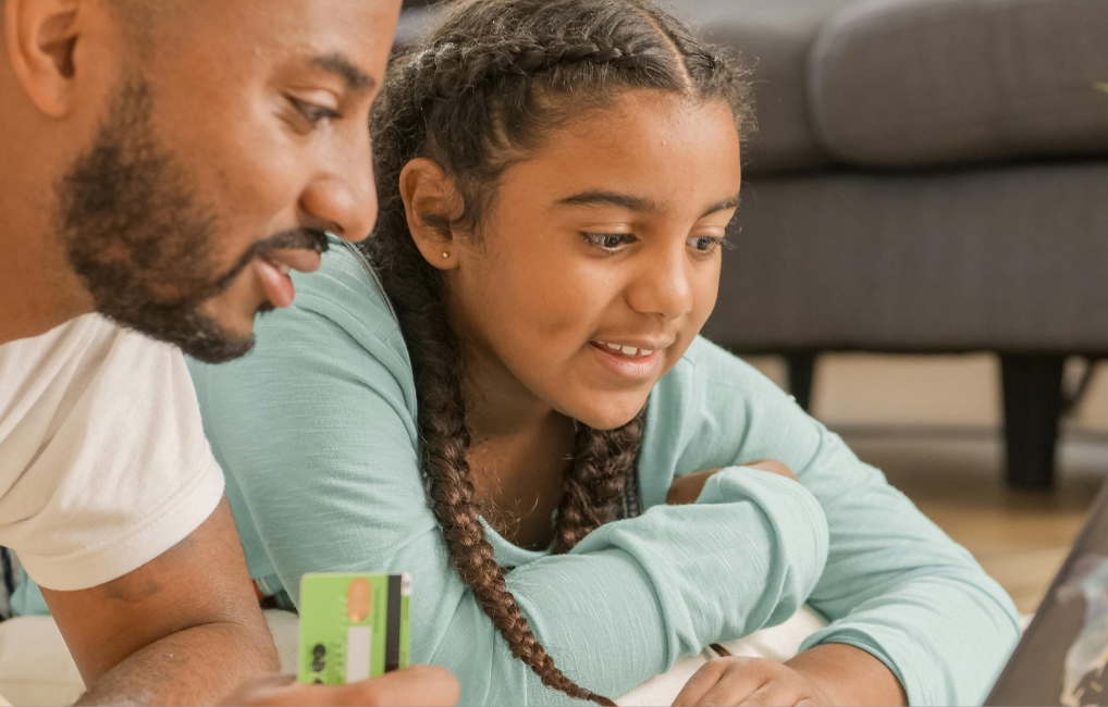 Father teaching daughter sitting at a laptop