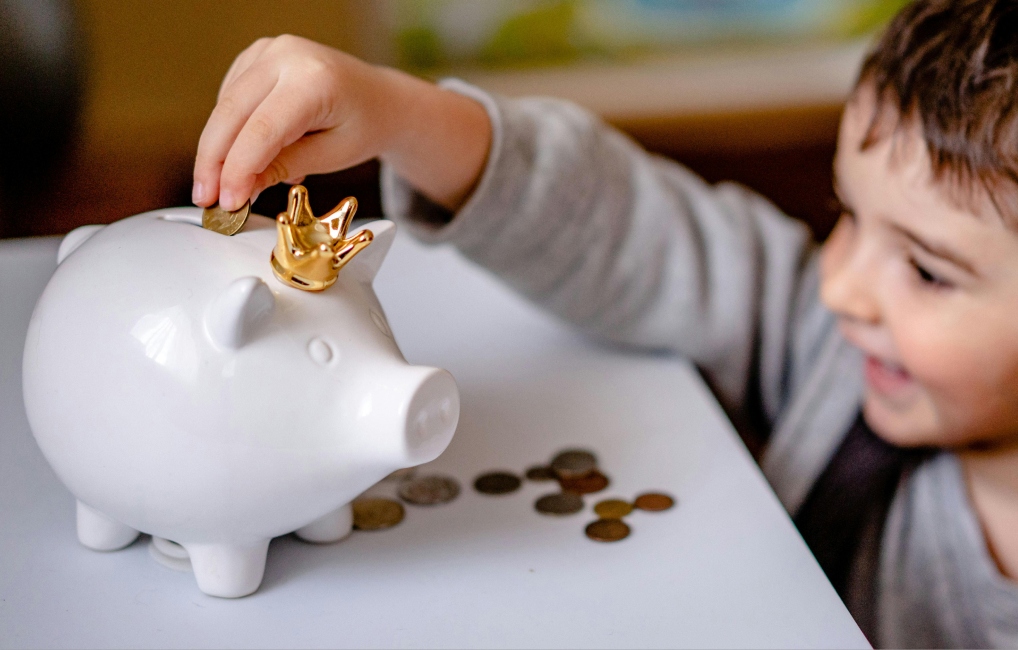 Child putting money in a piggy bank