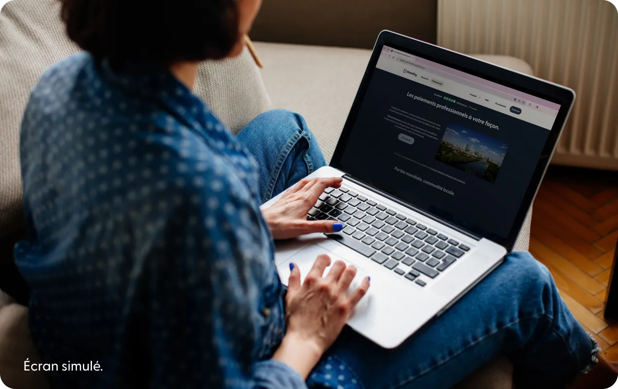 Personne utilisant un ordinateur portable et affichant une page d'accueil simulée de Remitly.