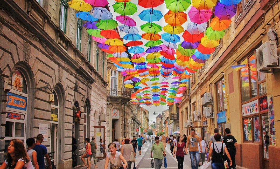 Busy street with colourful umbrellas hanging from above