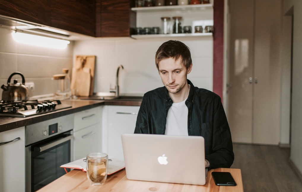 Man working remotely on his kitchen table with a laptop